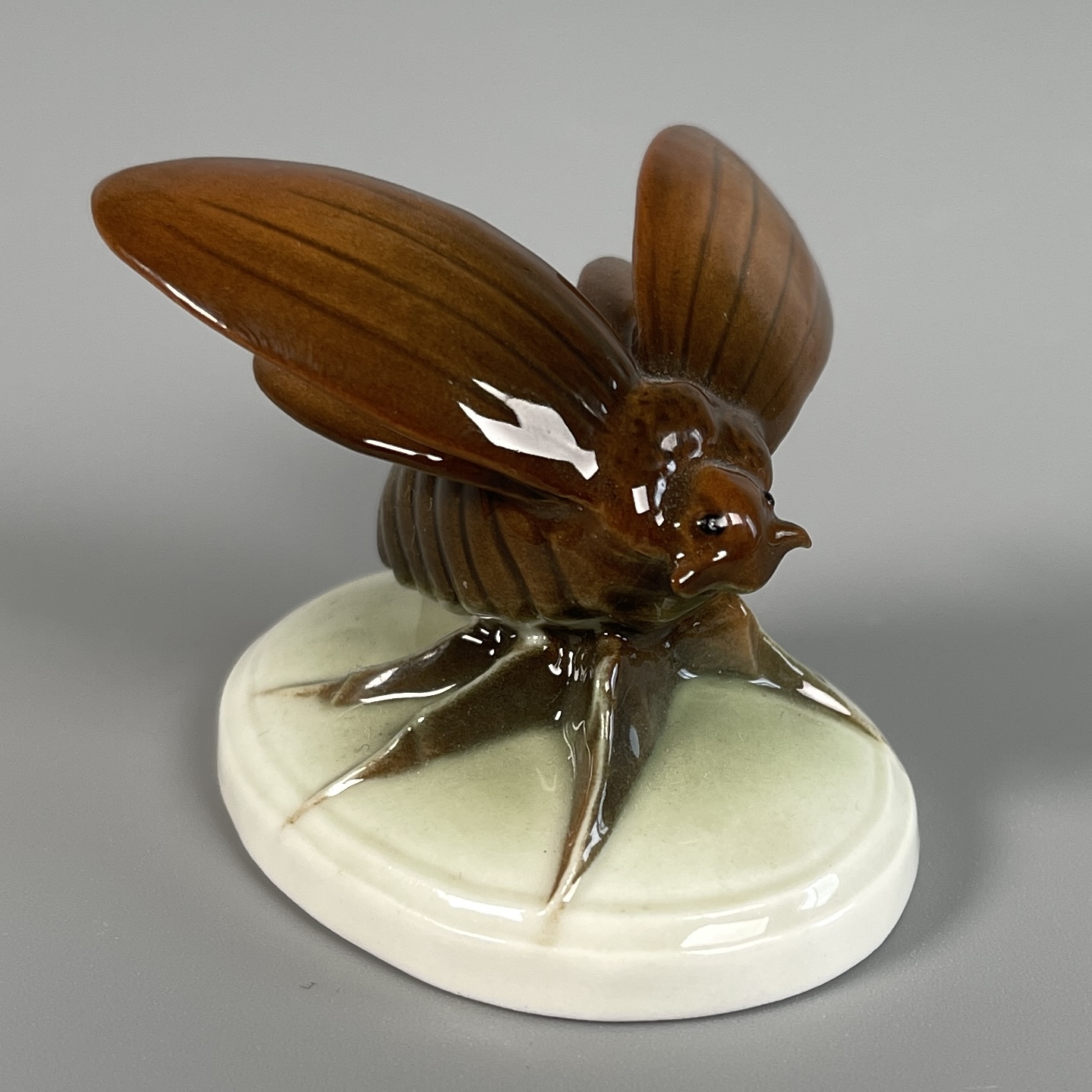 Maikäfer, auffliegend, auf ovalem Postament